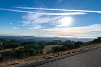 there are many clouds above the horizon and mountains in this picture of a wide open road