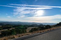 there are many clouds above the horizon and mountains in this picture of a wide open road