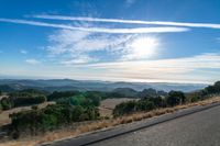 there are many clouds above the horizon and mountains in this picture of a wide open road