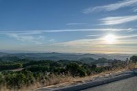 there are many clouds above the horizon and mountains in this picture of a wide open road