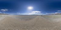 a desert landscape with a wide blue sky and mountains beyond it in the background, you can see an aerial 360 - angle view