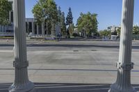 a wide open street with several columns in front of it and trees and a bus in the distance
