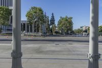 a wide open street with several columns in front of it and trees and a bus in the distance