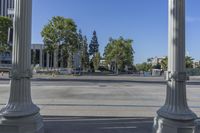 a wide open street with several columns in front of it and trees and a bus in the distance