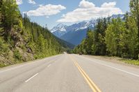 the long, wide, empty road stretches down to the mountainside in canada's west