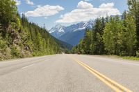 the long, wide, empty road stretches down to the mountainside in canada's west