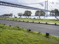 a wide road in front of a bridge and some grass on the side of it