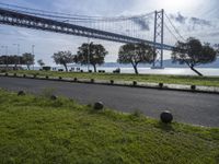 a wide road in front of a bridge and some grass on the side of it