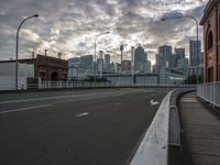 a wide roadway leads into a large city skyline with skyscrapers in the distance at sunset