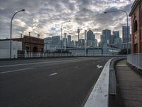 a wide roadway leads into a large city skyline with skyscrapers in the distance at sunset