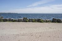 a brick path between two rocks near a beach and the ocean is very wide water