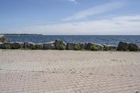 a brick path between two rocks near a beach and the ocean is very wide water