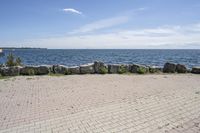 a brick path between two rocks near a beach and the ocean is very wide water