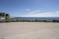 a brick path between two rocks near a beach and the ocean is very wide water