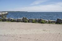 a brick path between two rocks near a beach and the ocean is very wide water