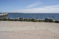 a brick path between two rocks near a beach and the ocean is very wide water