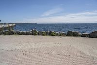 a brick path between two rocks near a beach and the ocean is very wide water