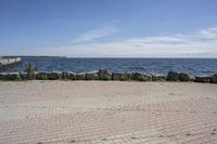 a brick path between two rocks near a beach and the ocean is very wide water