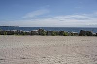 a brick path between two rocks near a beach and the ocean is very wide water