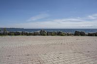 a brick path between two rocks near a beach and the ocean is very wide water