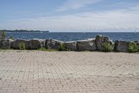 a brick path between two rocks near a beach and the ocean is very wide water