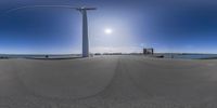 an image of a 360 camera fish eye view of wind turbine located on concrete at the beach