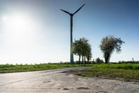 a person is walking down a paved path near wind turbines on a bright sunny day