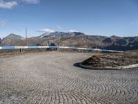 a winding cobbled walkway with blue railings to the side of a mountainous area