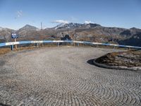 a winding cobbled walkway with blue railings to the side of a mountainous area