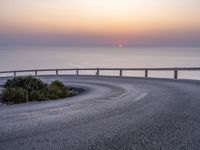 a winding curve near the ocean at sunset on a road between two lakes with bridge leading to water