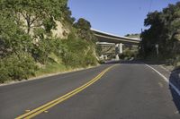a winding road runs between two highways above a valley with trees and bushes on either side