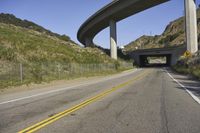 a winding road runs between two highways above a valley with trees and bushes on either side