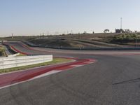 an empty track at a motorsports club with some red and white stripeing on it