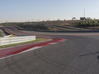 an empty track at a motorsports club with some red and white stripeing on it