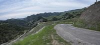 the winding road is empty, in the mountains in the background is green hills and trees