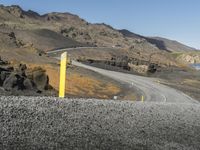 the winding road is in the desert with a yellow sign for traffic ahead of it