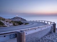 a view of a winding road with light shining on it at dusk in the background