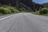 a motorcycle is riding along the winding road by some mountains in wyoming, usa, with a green patchy bushbery