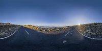 a winding road with white markings on the ground in the middle of the mountains and an empty street that goes past it