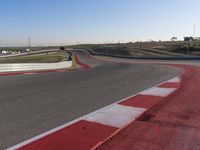 an empty track at a motorsports club with some red and white stripeing on it