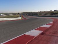 an empty track at a motorsports club with some red and white stripeing on it