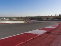 an empty track at a motorsports club with some red and white stripeing on it