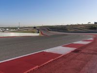 an empty track at a motorsports club with some red and white stripeing on it