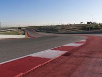 an empty track at a motorsports club with some red and white stripeing on it