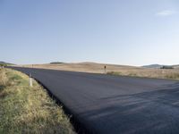 the road that is winding around and wide open grass on both sides of the road