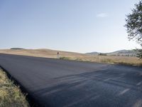 the road that is winding around and wide open grass on both sides of the road