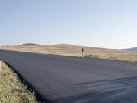 the road that is winding around and wide open grass on both sides of the road