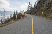 the winding road is empty and empty on both sides of the cliff, while a yellow warning sign marks the side