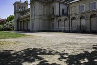 the two story castle sits in a field with green grass and trees, which are beside its gated area