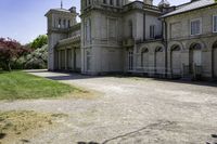 the two story castle sits in a field with green grass and trees, which are beside its gated area